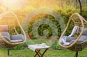 Rattan garden swing with cushion in the garden, seating area in the yard. Summer vacation concept