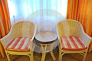 Rattan relax chairs and round table near the window