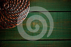 Rattan round lid on wooden green boards. Bright green wood structure as a background texture vignette