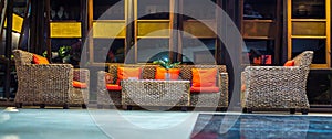 Rattan sofa with orange cushion in the lobby of a hotel