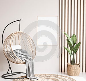 Rattan swing with green plant and rattan basket on wooden interior background, frame mockup