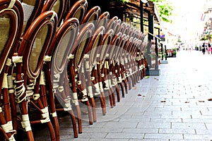 Rattan terrace chairs stacked along restaurant patio and city street
