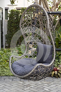 Rattan wicker cocoon garden swing chair hanged on frame. Recreation scene with a hammock-chair in the backyard of the house.