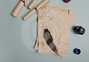 Raven feather, inkwell and old yellowed paper on red background. Copy space