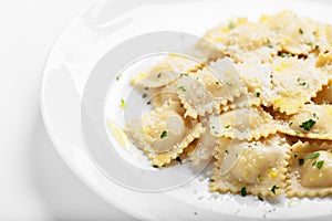 Ravioli with basil and parmesan on a white plate. White wine. Copy space. Close. Italian Cuisine