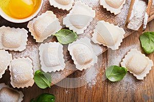 Ravioli Italian food. Tasty homemade pasta ravioli with flour, tomatoes, eggs and greens basil on wooden background. Process of