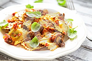 Ravioli with mushrooms and fresh basil. Bright wooden background.