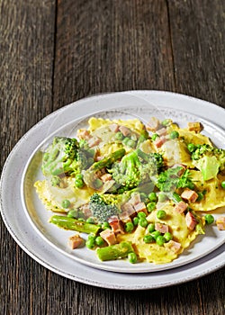 ravioli primavera with ham on a grey plate