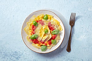 Ravioli with tomato sauce and basil on a plate, overhead shot with a fork