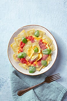 Ravioli with tomato sauce and fresh basil leaves, shot from above