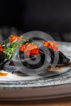 Ravioli with ton, caviar and Bechamel sauce. Black pelmeni, Dumplings