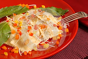 Ravioli topped with diced red, yellow and orange peppers with ba