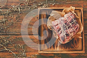 Raw aged prime black angus beef in craft papper on rustic wood