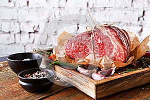 Raw aged prime black angus beef in craft papper on rustic wood