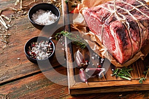 Raw aged prime black angus beef in craft papper on rustic wood