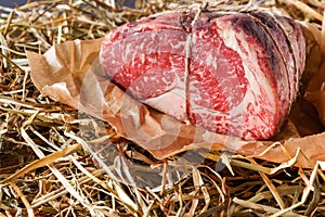 Raw aged prime black angus beef in craft papper on straw