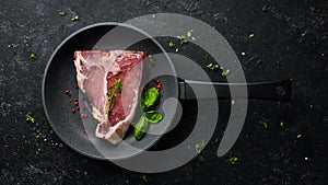 Raw aged T-bone steak on a black stone background. Top view. Rustic style
