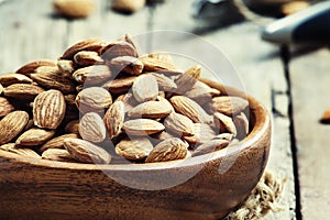 Raw almonds in bowls, old wooden background, selective focus