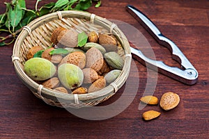 Raw almonds, peeled, with peel, skin almendrucos and almond leaves. On dark wood background.Basket with raw, peeled, shelled