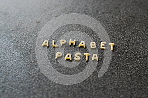 Raw Alphabet Pasta is Written with Letters on Granit Grey Surface.