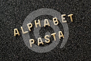 Raw Alphabet Pasta is Written with Letters on Granit Grey Surface.