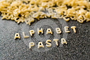 Raw Alphabet Pasta is Written with Letters on Granit Grey Surface.