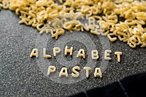 Raw Alphabet Pasta is Written with Letters on Granit Grey Surface.
