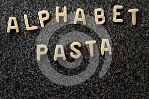 Raw Alphabet Pasta is Written with Letters on Granit Grey Surface.