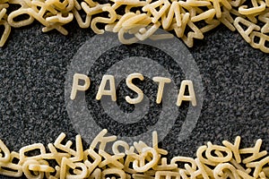 Raw Alphabet Pasta is Written with Letters on Granit Grey Surface.