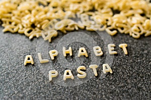 Raw Alphabet Pasta is Written with Letters on Granit Grey Surface. photo