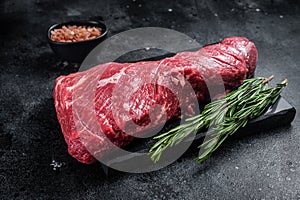 Raw American Tri Tip beef steak on marble board. Black background. Top view