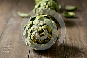 Raw artichokes on a wooden surface