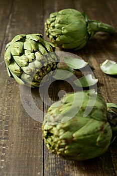 Raw artichokes on a wooden surface