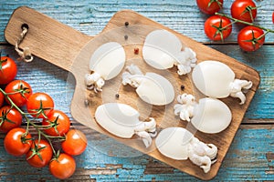 Raw babies cuttlefish on a cutting board with tomatoes