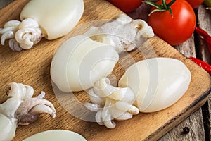 Raw babies cuttlefish on a cutting board with tomatoes