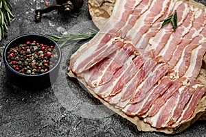 Raw bacon, bacon strips meat slice thin slicing pork fat meal on a dark background, ketogenic diet, place for text, top view