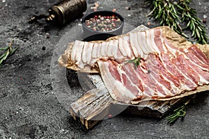 Raw bacon, bacon strips meat slice thin slicing pork fat meal on a dark background, ketogenic diet, place for text, top view