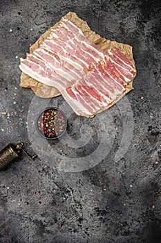 Raw bacon, bacon strips meat slice thin slicing pork fat meal on a light background, ketogenic diet, vertical image. top view.