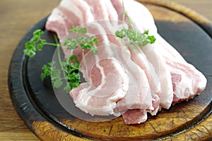 Raw bacon with parsley on white plate