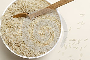 Raw basmati rice in a white bowl with a wooden spoon on a light background. Concept of Water-Conserving Products. Saving water.