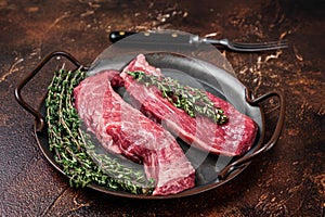 Raw Bavette or Sirloin flap beef meat steak with thyme. Dark background. Top view