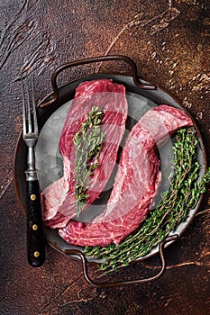 Raw Bavette or Sirloin flap beef meat steak with thyme. Dark background. Top view