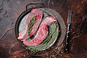 Raw Bavette or Sirloin flap beef meat steak with thyme. Dark background. Top view