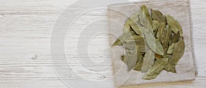 Raw Bay Leaves on a white wooden surface, top view. Flat lay, overhead, from above. Copy space