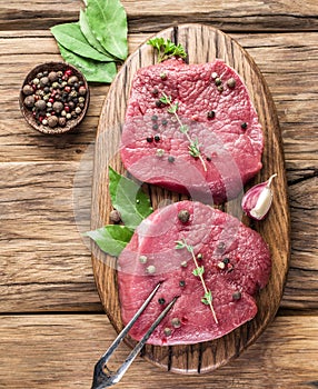 Raw beaf steaks with spices on a wood. photo