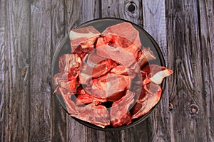 Raw beef bones in round clay bowl on wooden table