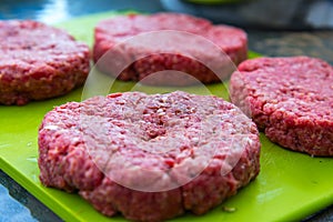 Raw beef burgers close up on a chopping board