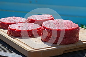 Raw beef burgers close up on a chopping board