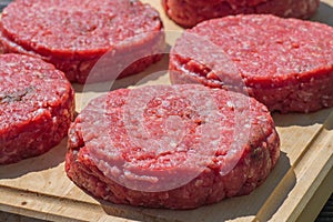 Raw beef burgers close up on a chopping board