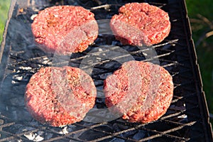 Raw beef burgers close up on a grill